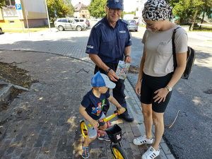 policjant wręcza kolorowankę chłopcu