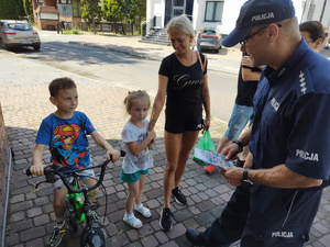 policjant wręcza kolorowankę chłopcu