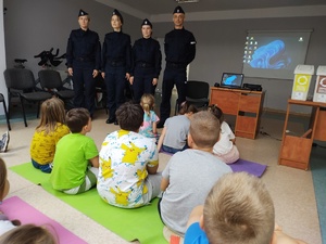 policjanci rozmawiają z dziećmi  w tle sala