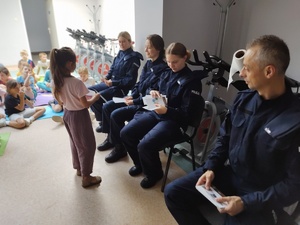 policjanci rozmawiają z dziećmi  w tle sala