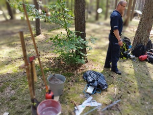 policjanci rozmawiają z harcerzami w tle las i namioty