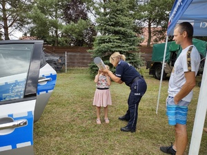 policjantka rozmawia z uczestnikami festynu w tle radiowóz i inne osoby