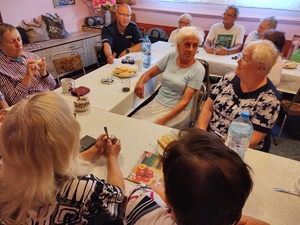 policjanci rozmawiają z seniorami w tle pomieszczenie PZN