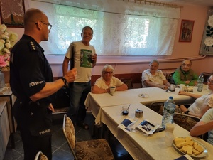 policjanci rozmawiają z seniorami w tle pomieszczenie PZN