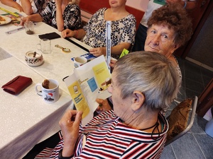 policjanci rozmawiają z seniorami w tle pomieszczenie PZN