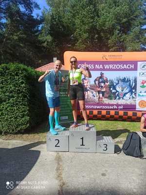 kobieta i mężczyzna na podium w tle banery i zieleń krzewów