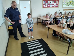 policjanci rozmawiają z dziećmi w tle sala lekcyjna i uczniowie