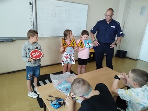 policjanci rozmawiają z dziećmi w tle sala lekcyjna i uczniowie