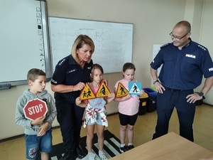 policjanci rozmawiają z dziećmi w tle sala lekcyjna i uczniowie
