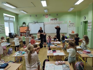 uczniowie ćwiczą bezpieczne postawy w tle sala i dzieci