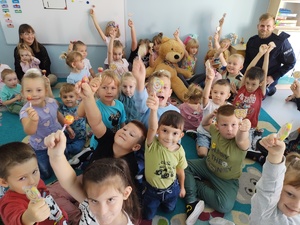 policjant i miś uczą dzieci pierwszej pomocy w tle sala