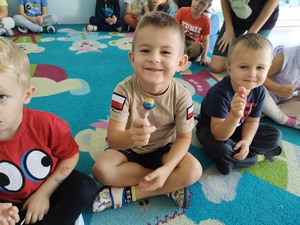 policjant i miś uczą dzieci pierwszej pomocy w tle sala