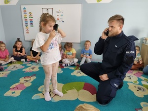 policjant i miś uczą dzieci pierwszej pomocy w tle sala