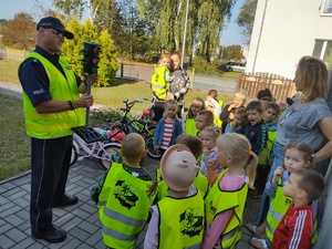 policjanci uczą dzieci chodzić po ulicy w tle ulica i maskotka policyjna