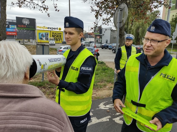 policjanci wręczają odblaski i prezentują odblaskową tubę