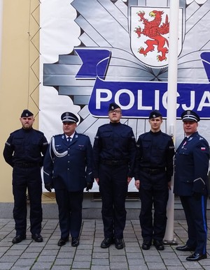policjanci w tle logo policji zachodniopomorskiej na ścianie budynku