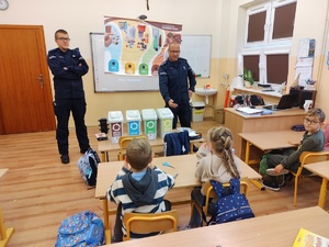 policjanci rozmawiają z dziećmi w tle sala lekcyjna