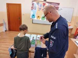 policjanci rozmawiają z dziećmi w tle sala lekcyjna