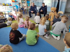 policjanci uczą dzieci pierwszej pomocy w tle sala