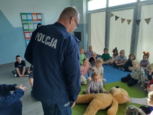 policjanci uczą dzieci pierwszej pomocy w tle sala