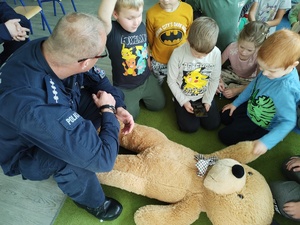 policjanci uczą dzieci pierwszej pomocy w tle sala