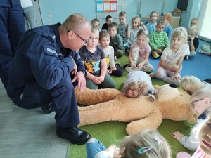 policjanci uczą dzieci pierwszej pomocy w tle sala