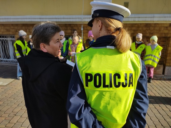 policjanci i uczniowie rozmawiają z kierowcami w tle zabudowania i ulica