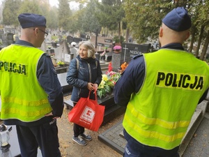 policjanci rozmawiają z kobietą przy grobie w tle groby