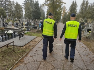 policjanci idą przez cmentarz w tle groby