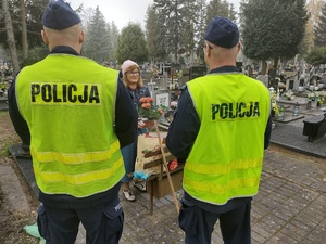 policjanci rozmawiają z kobietą przy grobie w tle groby