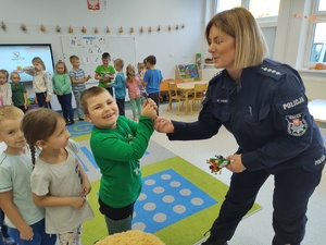 policjantka przybija piątkę z chłopcem w tle inne dzieci