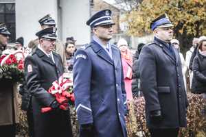 policjanci podczas uroczystych obchodów na placu Wolności w tle drzewa i inne ososby