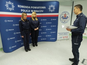 Komendant wręcza awanse w tle ścianka z logo policji