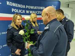 Komendant wręcza awanse w tle ścianka z logo policji