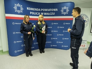 Komendant wręcza awanse w tle ścianka z logo policji