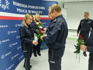 składanie życzeń i gratulacji w tle ścianka z logo policji