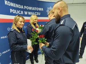 składanie życzeń i gratulacji w tle ścianka z logo policji