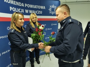 składanie życzeń i gratulacji w tle ścianka z logo policji