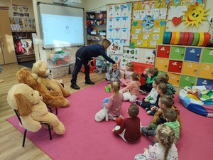 policjantka rozmawia z dziećmi w tle pluszowe misie i wyposażenie sali