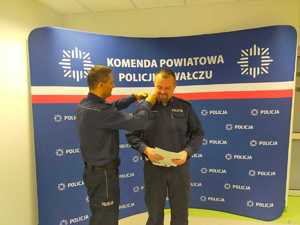 wręczenie awansu w tle ścianka z logo policji