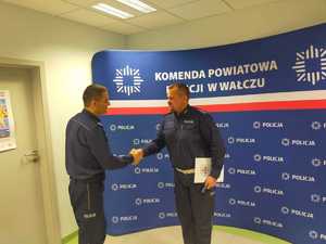 wręczenie awansu w tle ścianka z logo policji