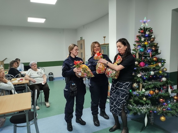 policjantki rozmawiają z seniorami w tle choinka i wyposażenie pomieszczenia