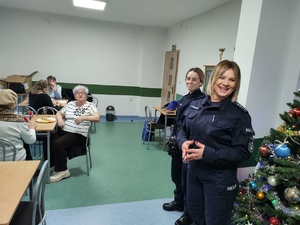 policjantki rozmawiają z seniorami w tle choinka i wyposażenie pomieszczenia