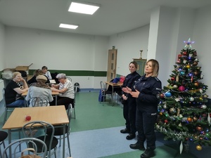 policjantki rozmawiają z seniorami w tle choinka i wyposażenie pomieszczenia
