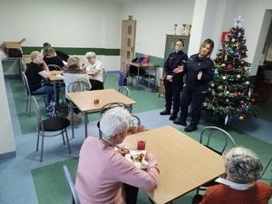 policjantki rozmawiają z seniorami w tle choinka i wyposażenie pomieszczenia