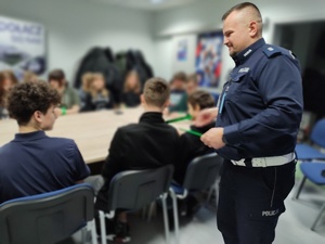 policjant rozdaje odblaski w tle wolontariusze i sala
