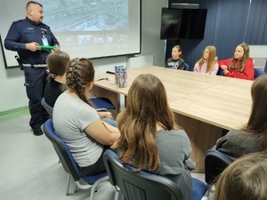 policjant rozmawia z wolontariuszami w tle banery i ekran