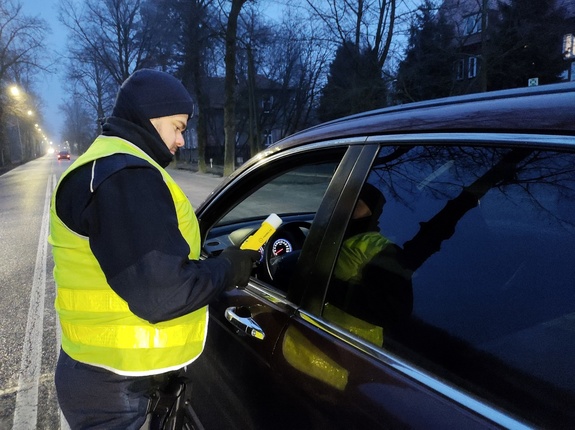 policjant bada stan trzeźwości w tle ulica i pojazdy