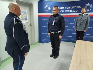 komendant wręcza awans i wyróżnienia policjantom w tle ścianka z logo policji