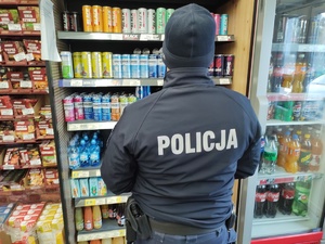 policjant rozmawia z ekspedientką w tle towar na półkach sklepowych